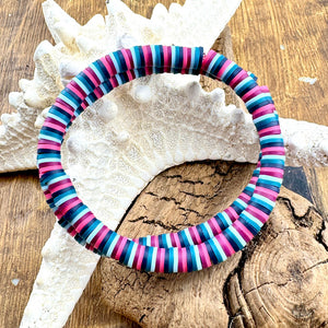 All Up In The Hair | Online Accessory Boutique Located in Mooresville, NC | Two pink, burgundy, teal and blue bracelets laying on a piece of driftwood and a starfish.