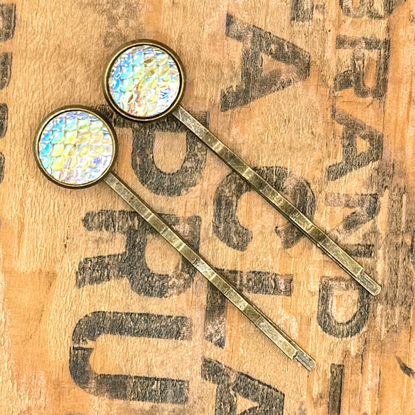 All Up In The Hair | Online Accessory Boutique Located in Mooresville, NC | Two Yellow Mermaid Bobby Pins laying on a wood background with black lettering.