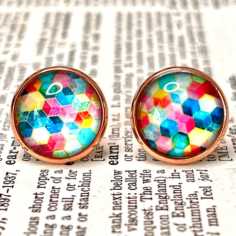 All Up In The Hair | Online Accessory Boutique Located in Mooresville, NC | Close up of a pair of round, multicolor earrings that have a cubic geometric print. The earrings are laying on a book page.